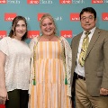 Three individuals stand together in front of a UTMB Health backdrop, with one wearing green honor cords over a striped dress, during an Alpha Omega Alpha Texas Alpha Chapter recognition event.