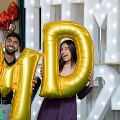 Two individuals stand indoors holding large gold “M” and “D” balloons in front of illuminated “UTMB 24” letters, with red, white, gold, and silver balloon arrangements on the side against a curtain backdrop.
