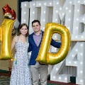 Two individuals pose in front of illuminated “UTMB 2024” letters holding large gold “M” and “D” balloons with red, white, and gold decorations at an Alpha Omega Alpha Texas Alpha Chapter event.
