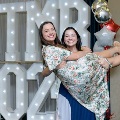 Two individuals pose in front of illuminated “UTMB 2024” display, with one holding the other horizontally, and red, white, and gold balloon decorations at an Alpha Omega Alpha Texas Alpha Chapter event.