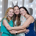 Three individuals stand closely together with arms around each other in front of illuminated “UTMB 2024” letters and red, white, and gold balloon decorations at an Alpha Omega Alpha Texas Alpha Chapter event.