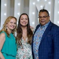 Three individuals stand together in front of illuminated “UTMB” letters at an Alpha Omega Alpha Texas Alpha Chapter event at the University of Texas Medical Branch.