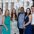 Six individuals stand together in front of illuminated “UTMB” letters with red, white, and gold balloon decorations at an Alpha Omega Alpha Texas Alpha Chapter event.