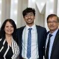 Three individuals stand together in front of illuminated “UTMB” letters with red, white, and gold balloon decorations at an Alpha Omega Alpha Texas Alpha Chapter event.