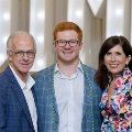 Three individuals pose closely together in front of illuminated “UTMB” letters at an Alpha Omega Alpha Texas Alpha Chapter event at the University of Texas Medical Branch.