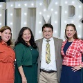 Four individuals pose together in front of illuminated “UTMB” letters with red, white, and gold balloon decorations at an Alpha Omega Alpha Texas Alpha Chapter event.