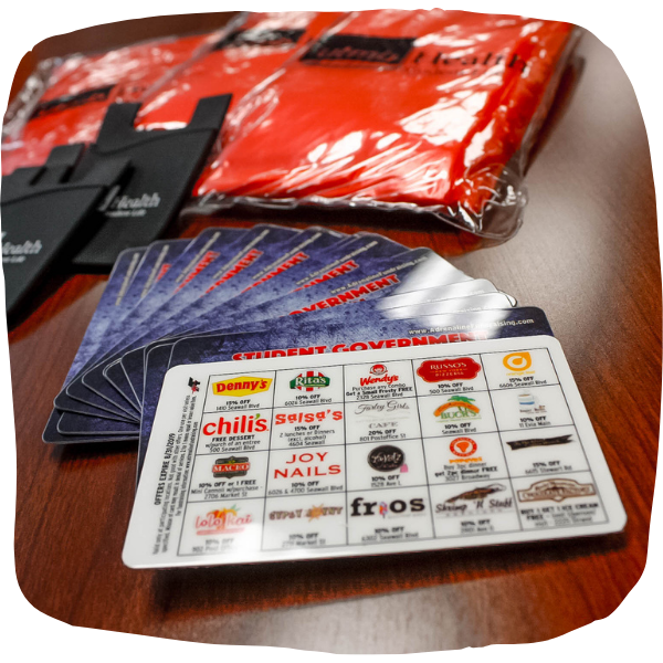 Discount cards, phone wallets, and rain ponchos are on a desk.
