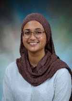 Professional portrait of Nashwa Hossain wearing a brown draped hijab and glasses in front of a blue and green backdrop