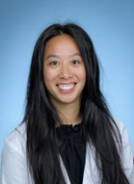 Professional headshot of Amber Ly with long black hair, wearing a black top under a whitecoat