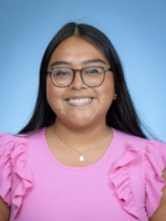 Professional headshot of Emily Enrriquez with long brown hair, wearing a pink top