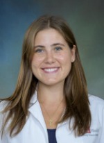 Professional headshot of Elizabeth McCarthy with medium length highlighted brown hair, wearing a navy top under a whitecoat