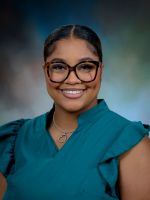 Professional headshot of Samirah Jackson with black hair in a bun, wearing a teal top and glasses