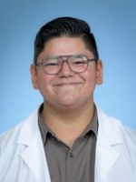 Professional headshot of Kevin Andrade with short black hair and glasses, wearing a gray top under a whitecoat