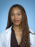 White Coat headshot of Lauren Are with long brown braids, wearing a brown top and whitecoat, in front of a blue background