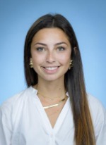 Professional headshot of Natalie Ramos with long  highlighted brown hair, wearing a white top
