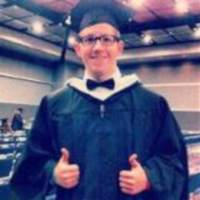 AJ Haney in graduation robe giving two thumbs up