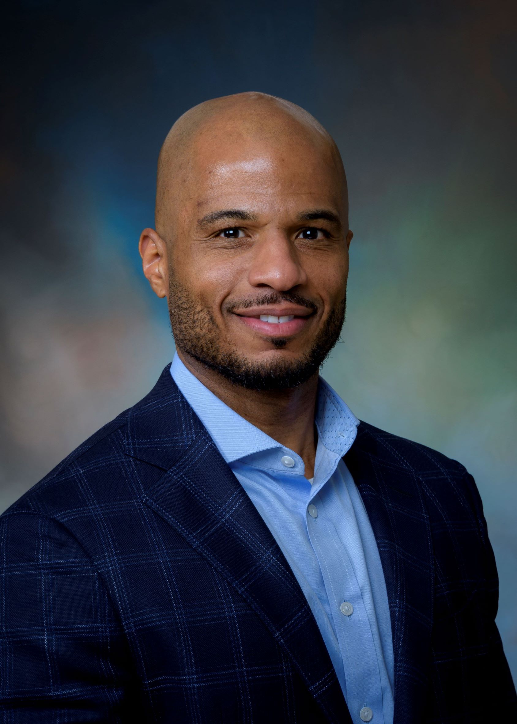 Formal studio portrait of Jamie D. Bailey, MBA, CPA, CFE, Executive Vice President and Chief Financial Officer at the University of Texas Medical Branch, wearing a dark checkered blazer and light blue dress shirt against a softly blurred background.