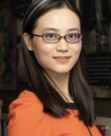 woman wearing glasses, smiling in professional dress in a studio setting