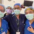 Four medical professionals in surgical scrubs, masks, and caps pose together in a clinical setting, representing the UTMB urogynecology fellowship team.