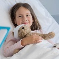 Child in hospital bed with a teddy bear
