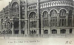 Black and white photograph of an ornate three storied building comprised on arches and angled brickwork.