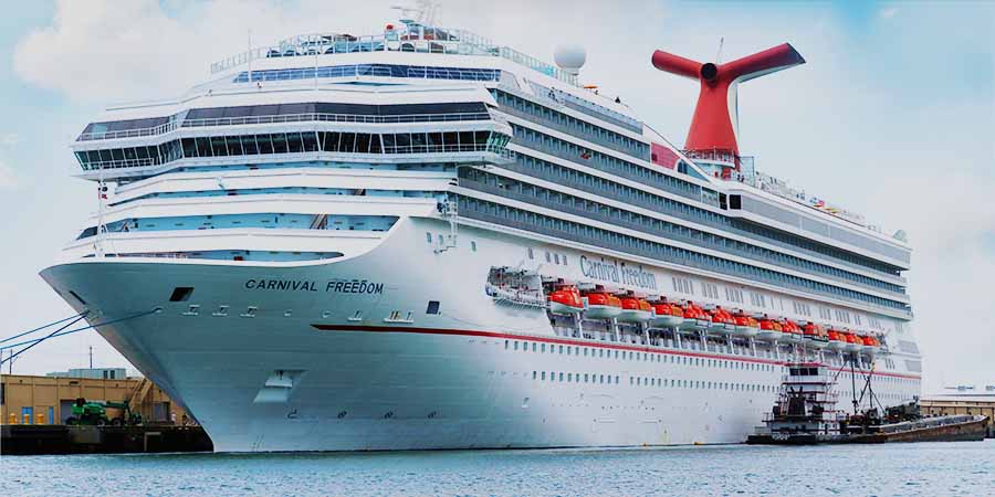 Large Carnival Cruise Line ship docked at the Port of Galveston, showing the white vessel with red funnel and lifeboats along the side, representing cruise travel supported by a new medical consultation partnership with UTMB Health