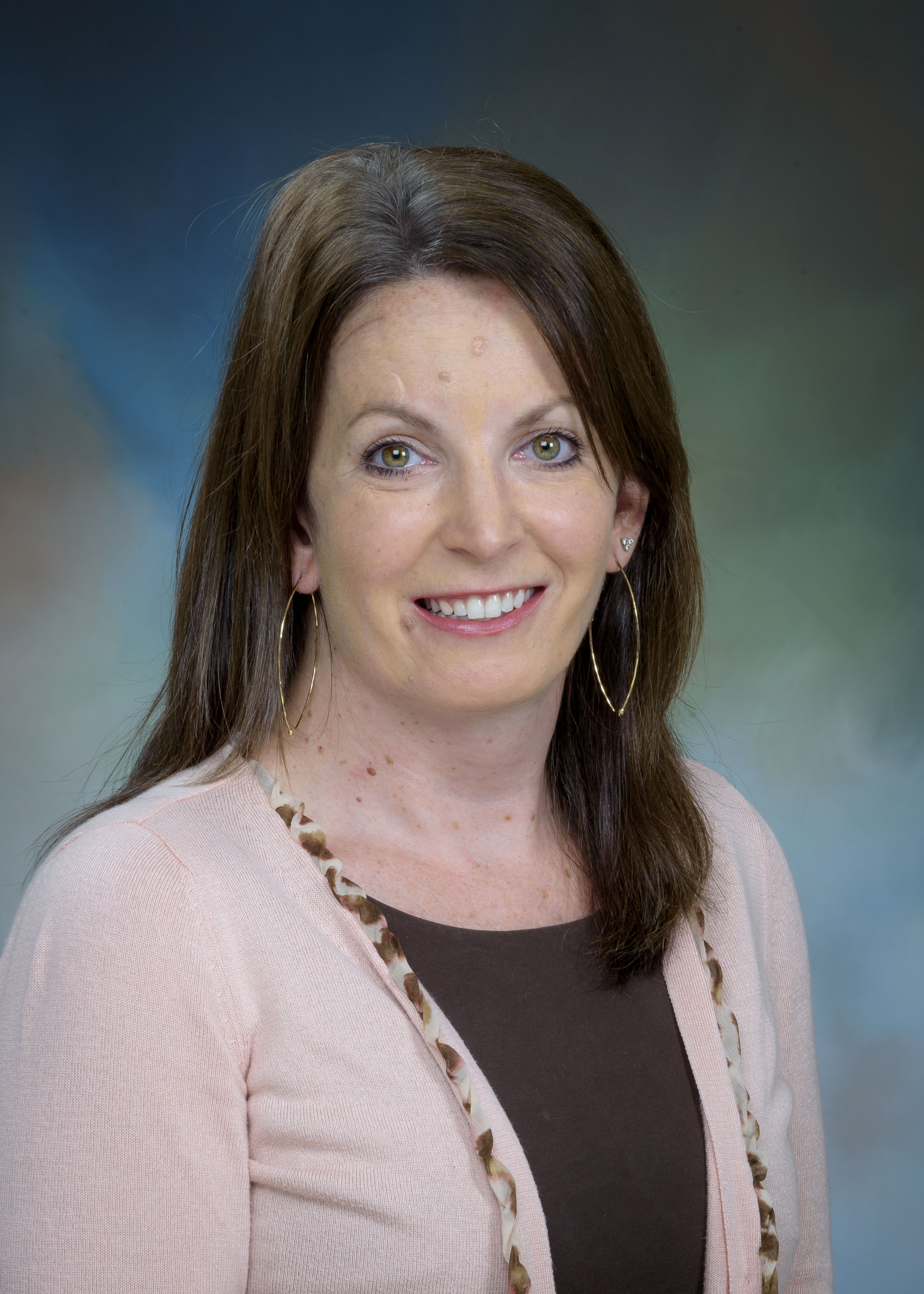 headshot image of clinical psychologist Dr. Barbara Calvert - a female clinician wearing a brown shirt with a pink cardigan and gold earrings