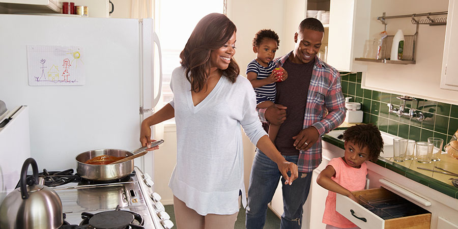 A mom cooking on the stove with a dad and two children in the kitchen