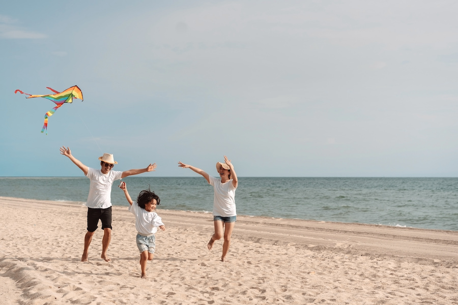 asian family running on the beach flying a kite