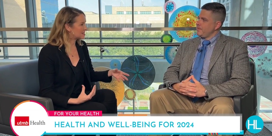 Melanie Camp, wearing black sitting in chair on the left, talking with Dr. Carlos Dostal, wearing a blue tie and gray blazer, seated in a chair on the right
