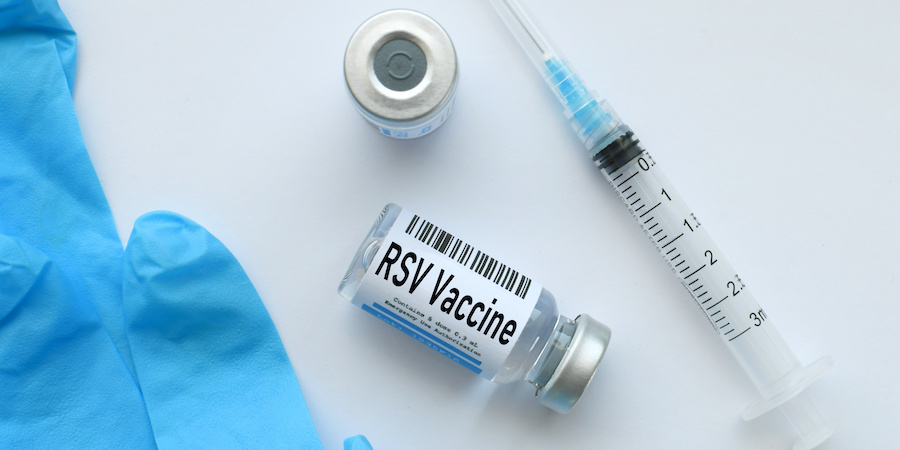 image of partial blue glove, a vile of the RSV vaccine laid over with a label that says "RSV Vaccine" , a vaccine vile standing up and a syringe