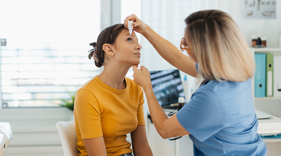 Pediatrician putting eye drops into girls eyes. The ophthalmologist treating an eye infection, allergy, or inflammation using prescribed eye drops.