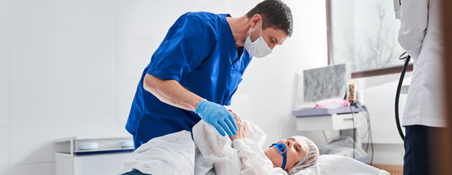 Male doctor talking with his female patient lying on hospital bed  before a colonoscopy