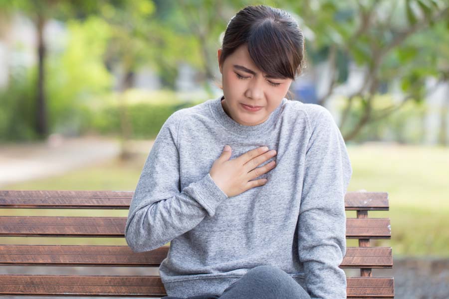 Woman with acid reflux disease pressing her fingers against sternum