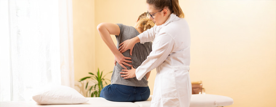 Female chiropractor examining the spine of female patient after a back injury at UTMB Health.