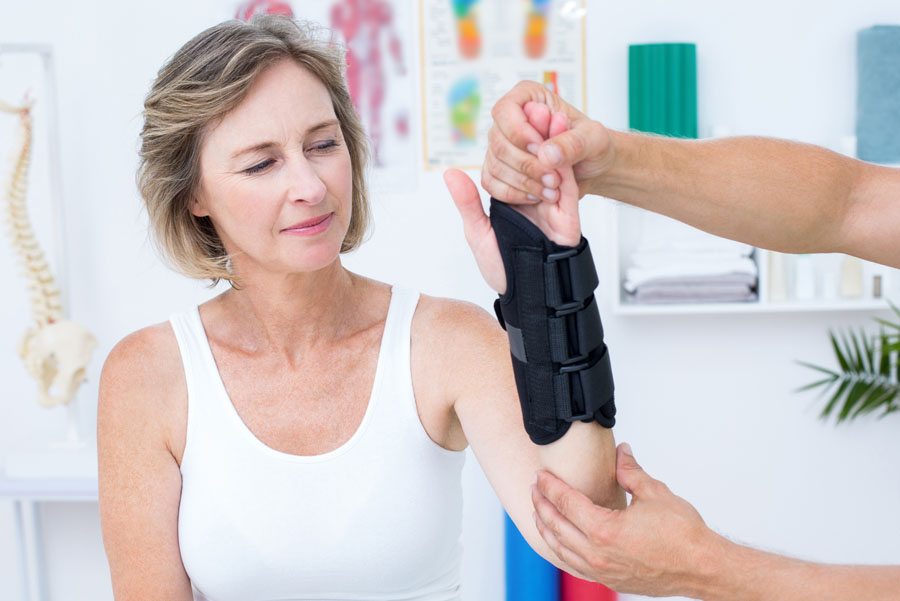 Female patient at UTMB Health wearing wrist brace while doctor examines her wrist.