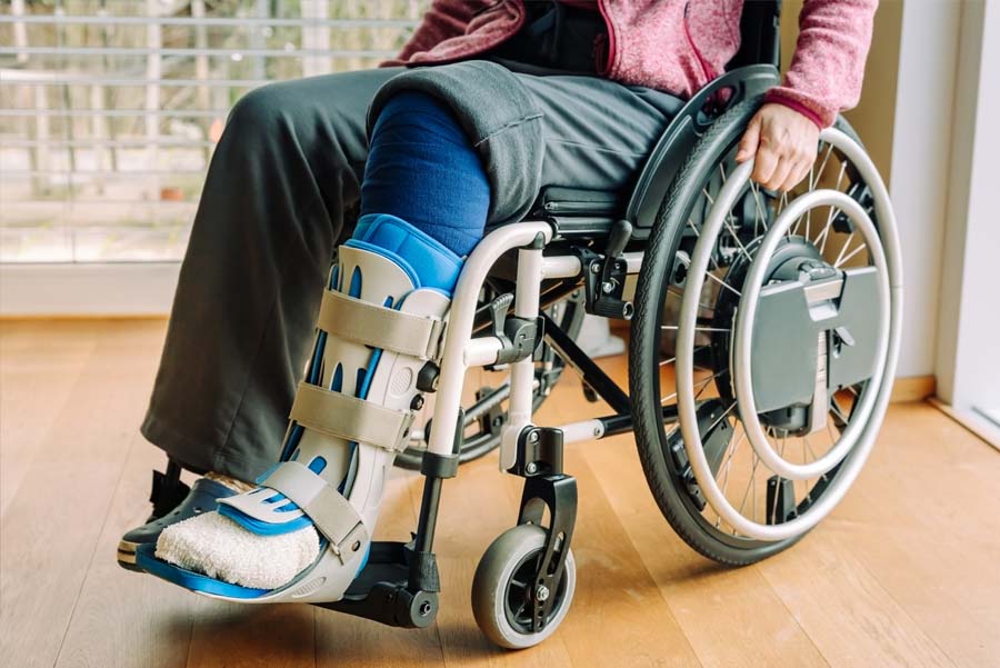 Closeup of man from waist down wearing a leg brace and sitting in a wheelchair at UTMB Health after an injury
