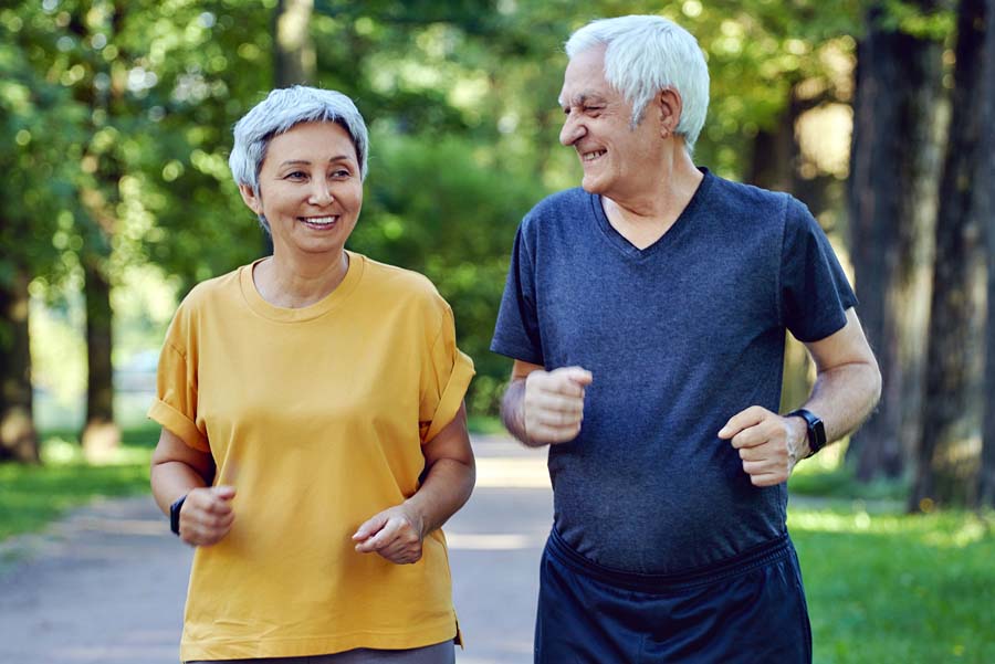 Happy elderly couple power walking along a trail