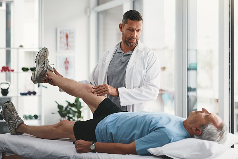 Physical therapist lifting patient’s leg during therapy session