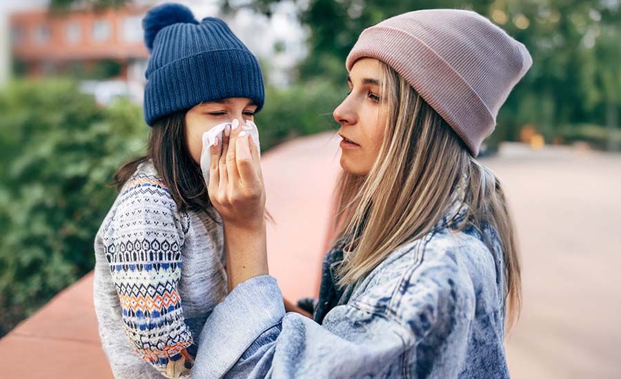 Mother wiping daughter's nose with tissue