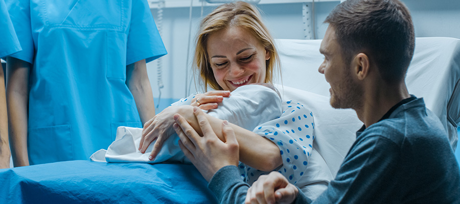 Parents hold their newborn baby together in a labor and delivery room at UTMB Health Angleton.