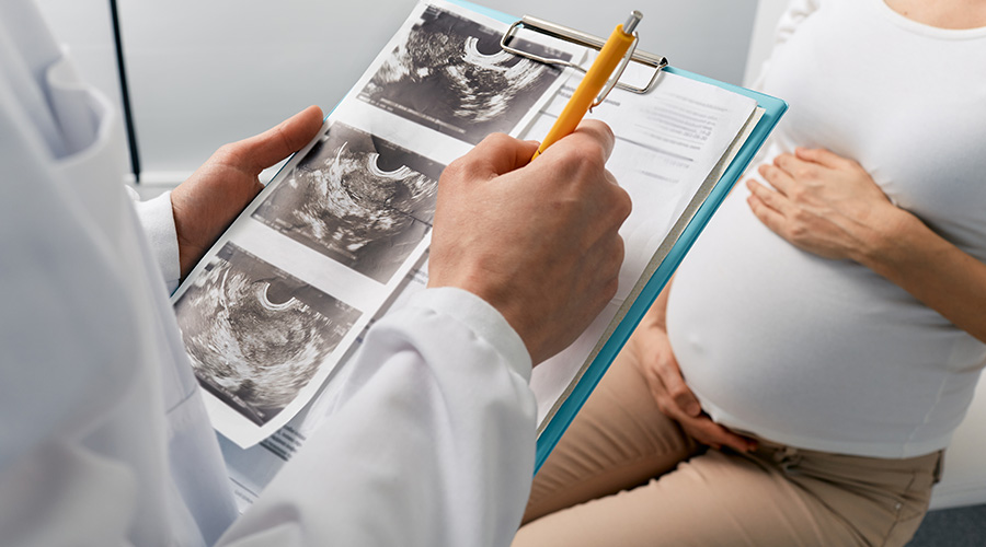 A maternal-fetal medicine provider reviews ultrasound images with a pregnant patient during a prenatal appointment.