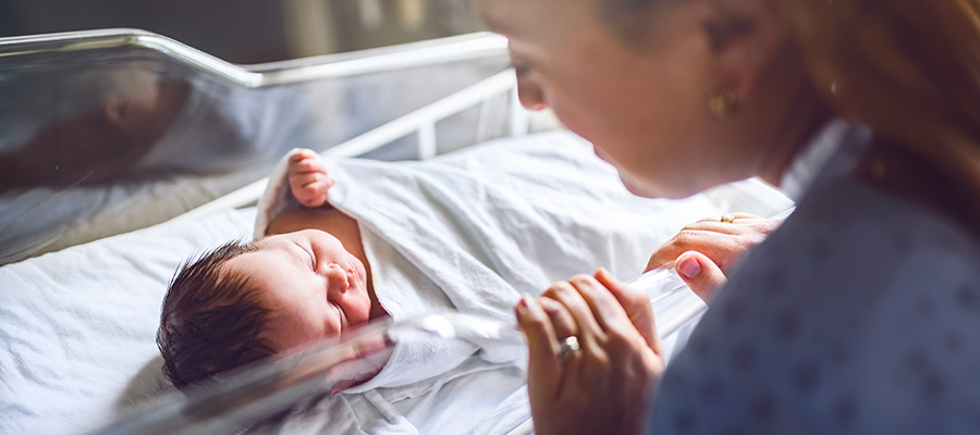 A newborn baby rests in a hospital bassinet as a parent looks on at UTMB Health Labor and Delivery in Clear Lake.