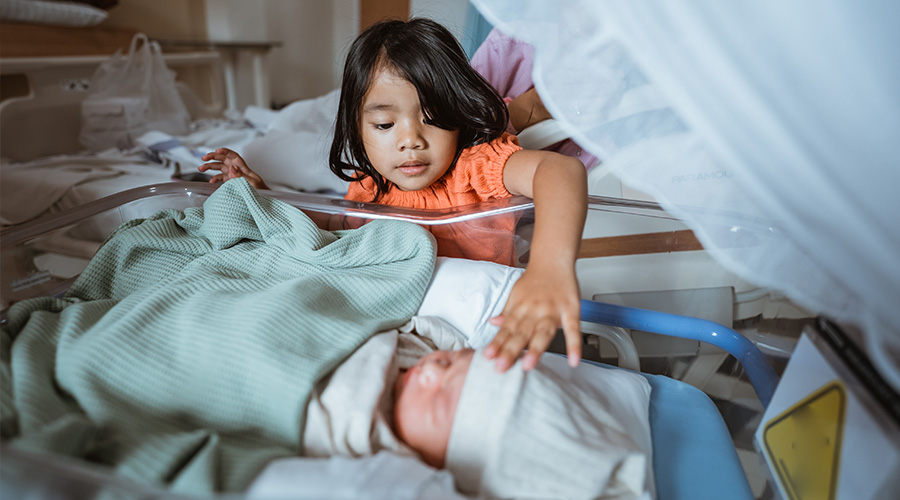 A young sibling gently touches a newborn baby during a family visit at UTMB Health Labor and Delivery in Angleton.