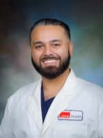Professional head‑and‑shoulders portrait of UTMB Health clinician, Dr. Kenny Kumar, wearing a white lab coat against a neutral studio background.