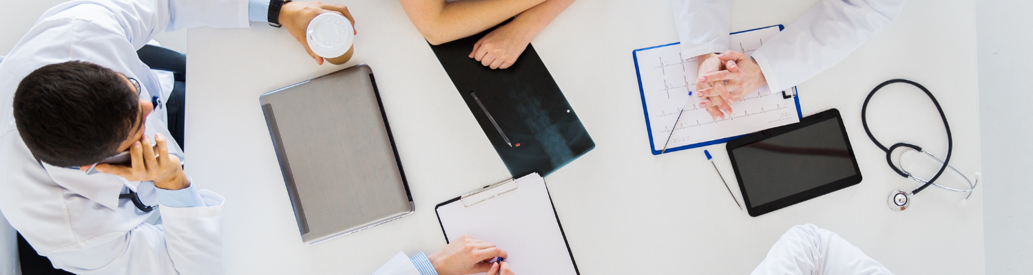 Top view of doctors sitting around a work table sharing notes and having a meeting