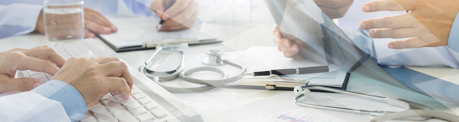 Stethoscope on a table. Doctors hands typing, writing, and holding papers