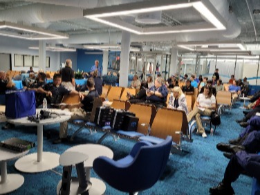 Large indoor operations room with multiple rows of seating, staff members using laptops and equipment, and open ceiling infrastructure with modern lighting.