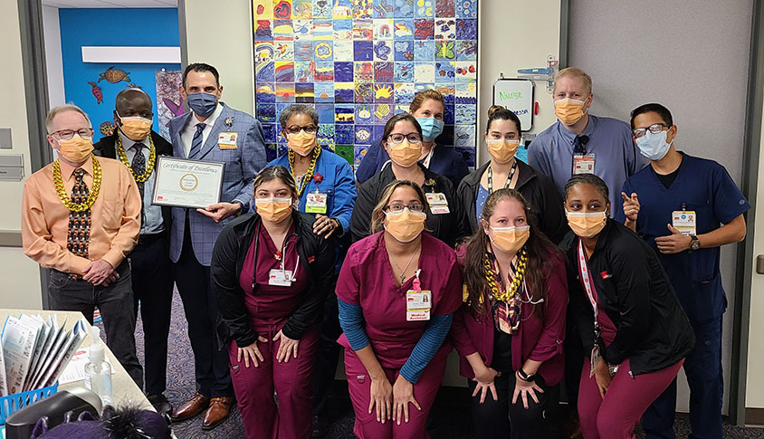 Class of students in masks kneeling in front of Pedi clinic