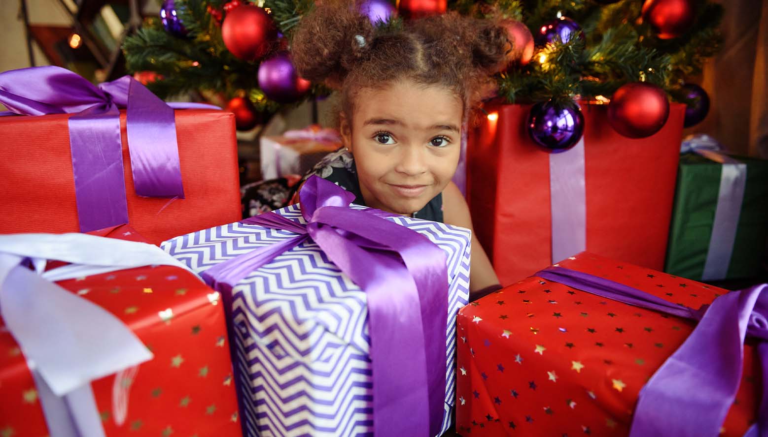 Girl under tree among many wrapped presents